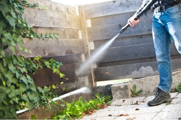 Man power washing fence.